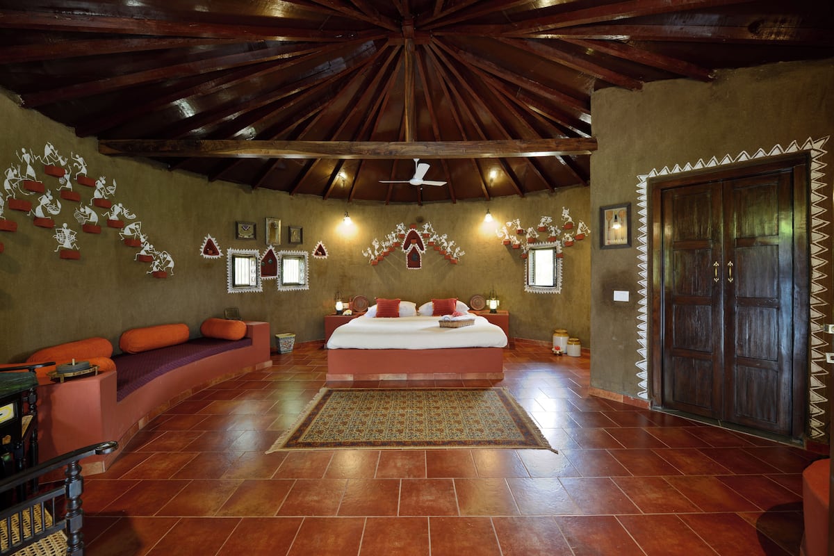 A spacious room with a large bed, a wooden ceiling, and a decorative wall.