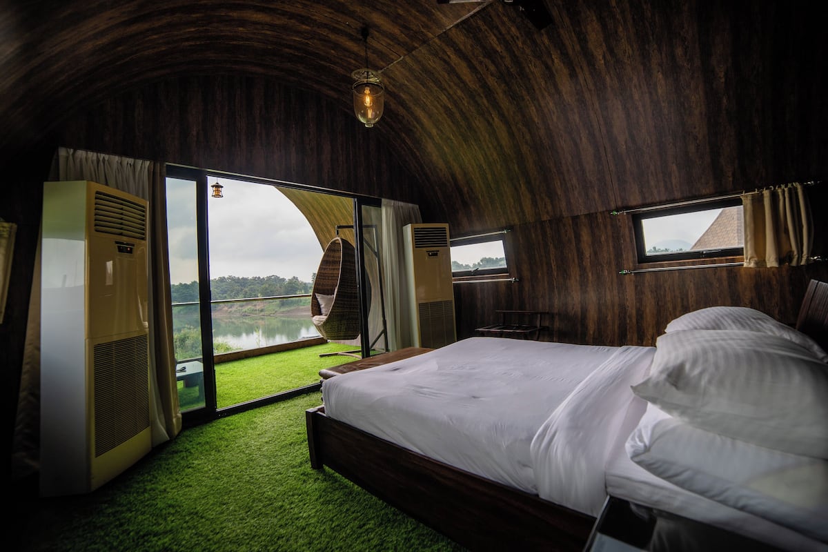 A bedroom with a large bed, a view of a lake, and a wooden ceiling.