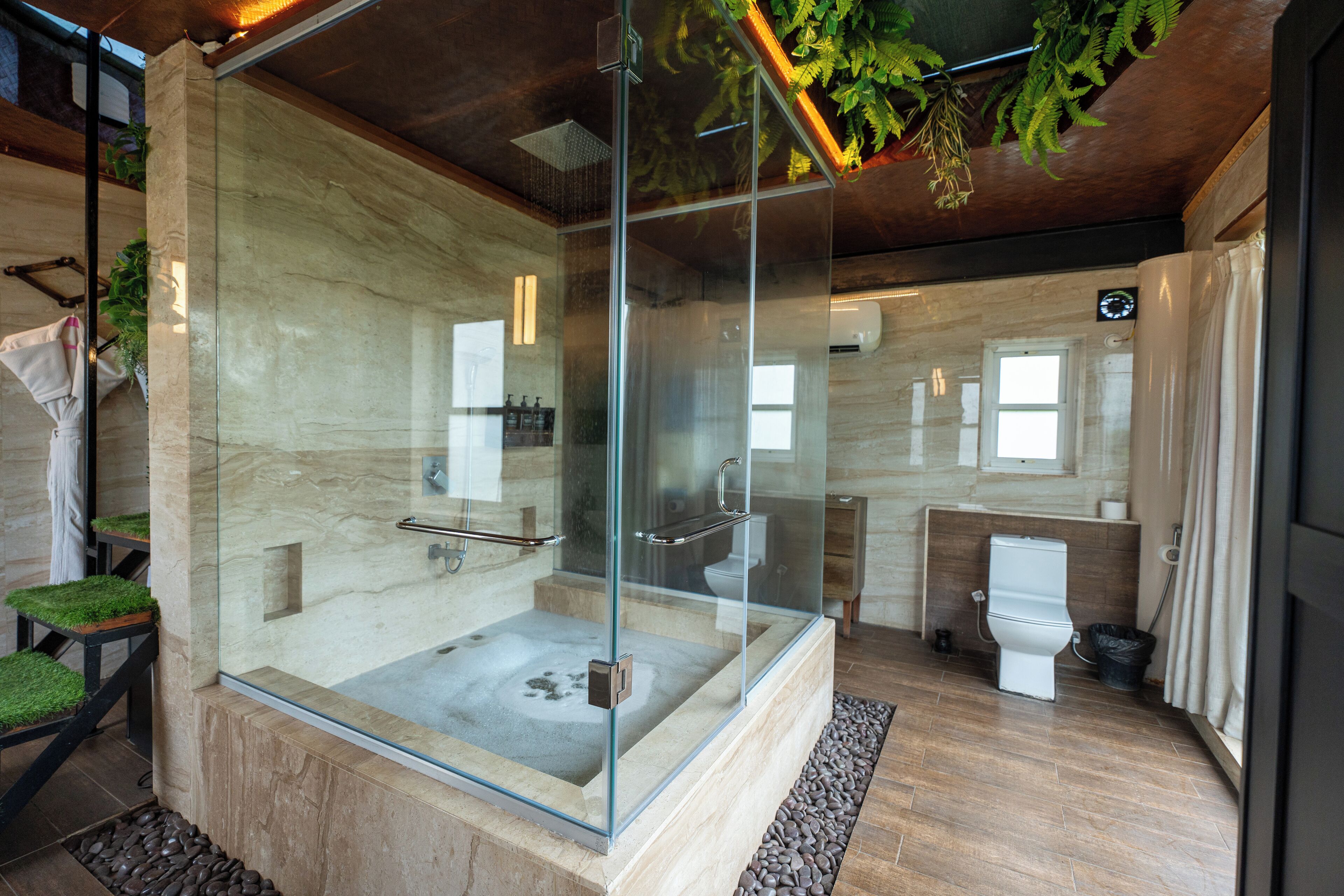 A modern bathroom with a glass-enclosed shower, a bathtub, and a toilet.