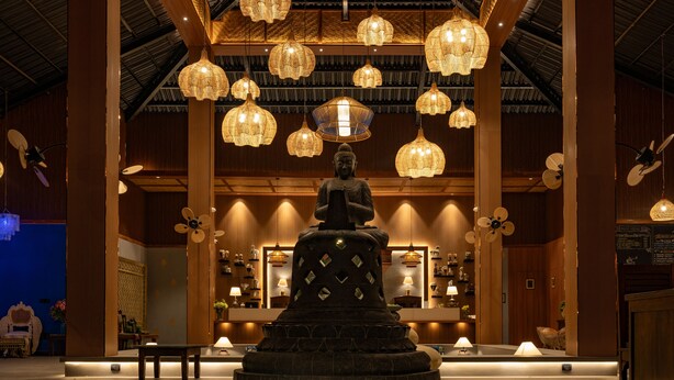 A statue in a well-lit lobby with hanging lights and wooden paneling. - Anchaviyo By Zuper (Vada)