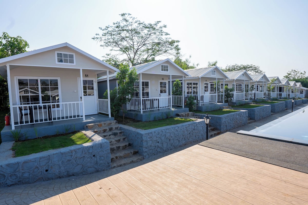 A row of white cabins with stone steps and a wooden deck.