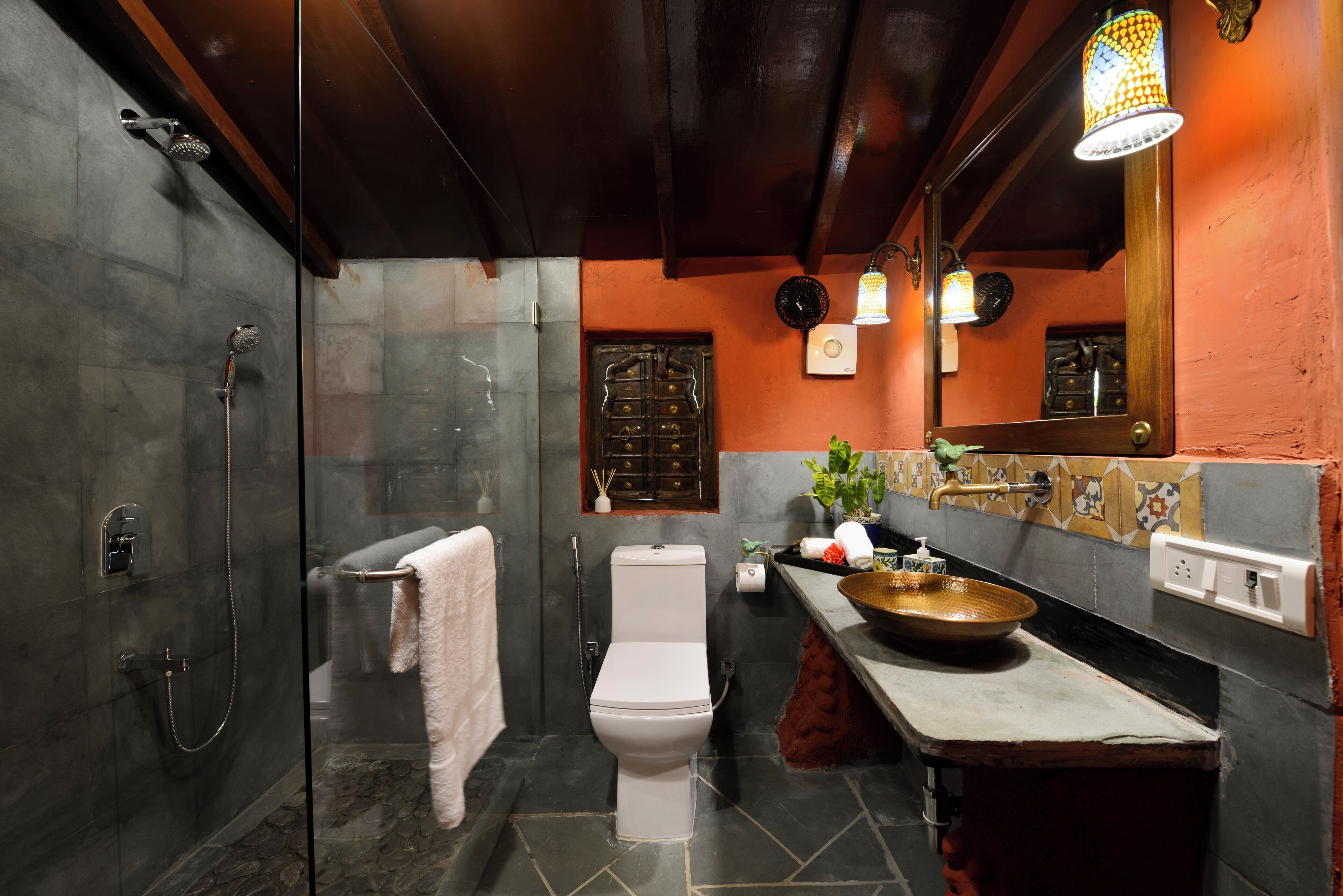 A bathroom with a glass-enclosed shower, a white toilet, and a sink with a decorative bowl.