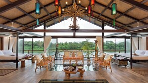 A spacious room with a large glass table, comfortable seating, and a view of a lush landscape. - Anchaviyo By Zuper (Vada)