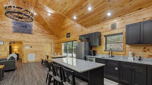 A log cabin interior with a kitchen, dining area, and a living room.