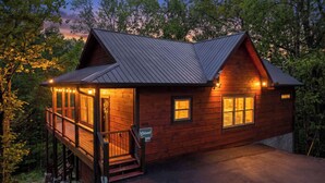 A wooden cabin with a balcony, a covered porch, and a number '1614' sign.