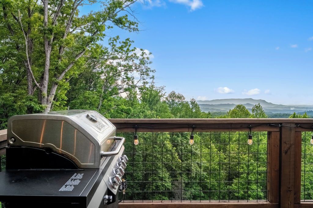 Una parrilla en un balcón con vistas a árboles y montañas distantes.