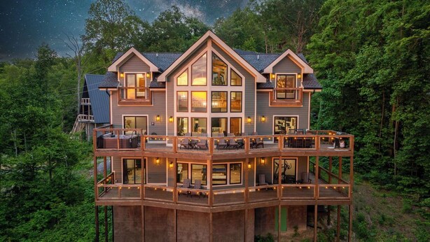 A multi-story house with a balcony, surrounded by trees.