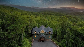 Uma casa rodeada por floresta densa, com vista nítida para o céu noturno.