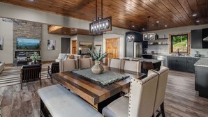 A spacious living area with a wooden ceiling, a dining table, and a kitchen with dark cabinets.
