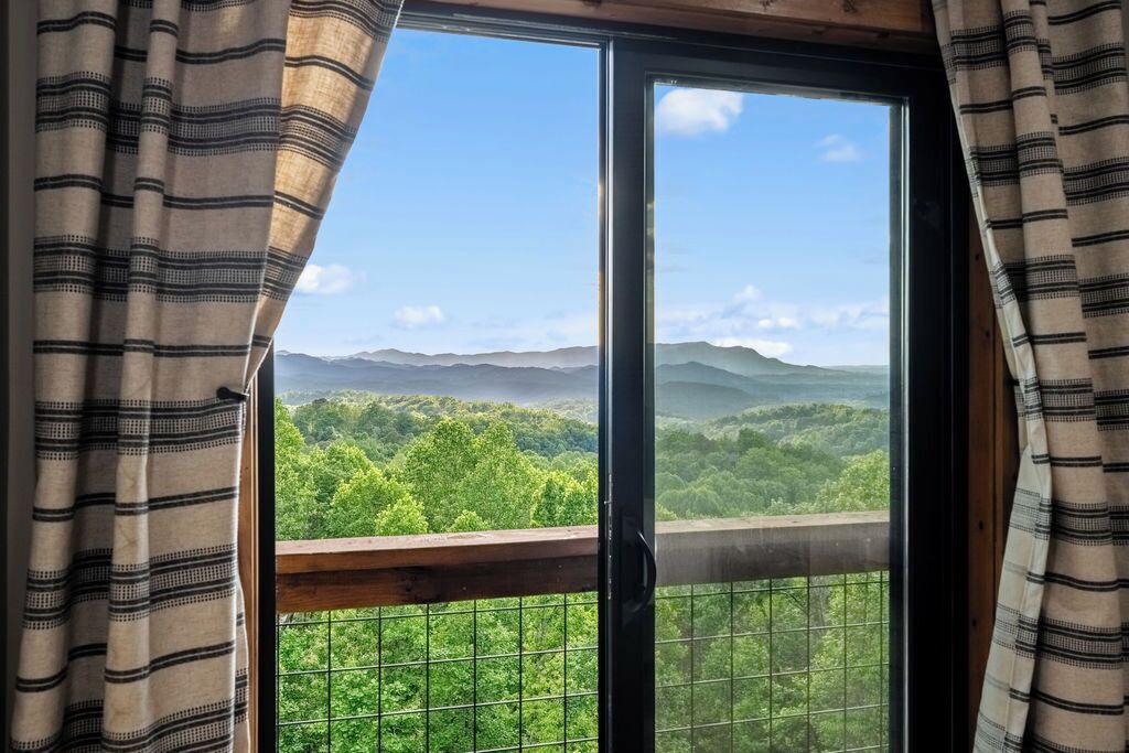 A window with a view of a forested mountain range.