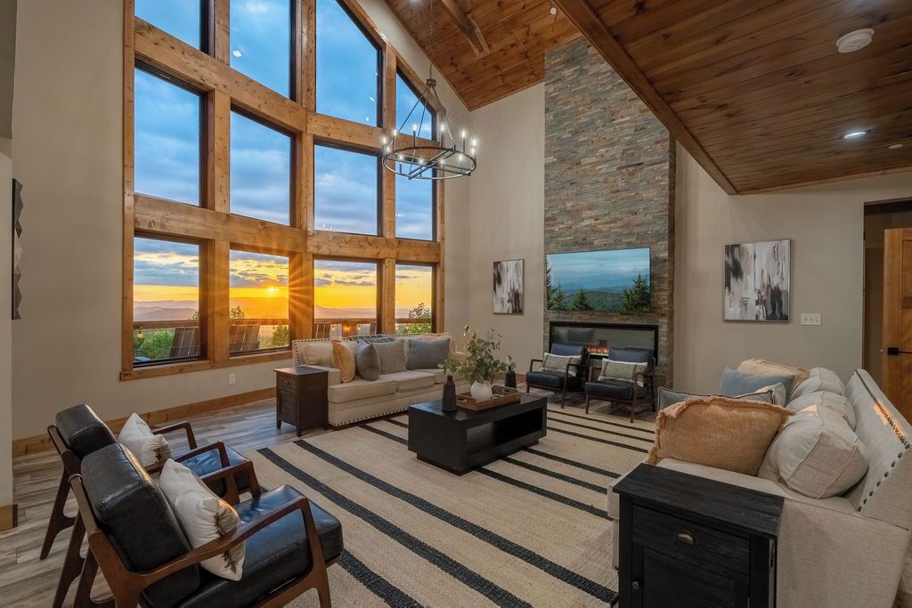 Un salón amplio con ventanas grandes, chimenea y un revestimiento de chimenea moderno.