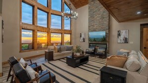 A spacious living room with large windows, a fireplace, and a modern fireplace mantel.