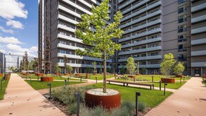 Ein modernes Stadtgebäude mit mehreren Stockwerken, einem zentralen Innenhof mit Bäumen und einem Fußweg.