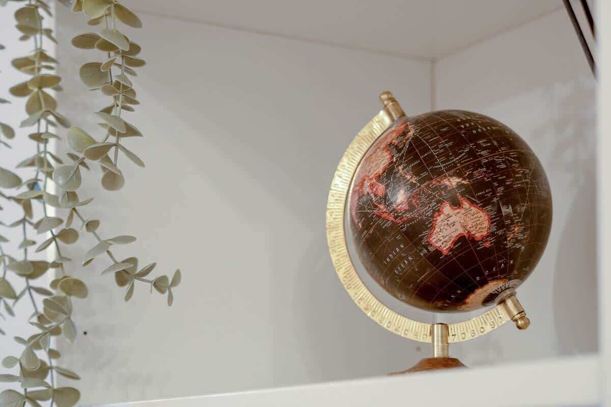 Un globo sobre un soporte, con una pared blanca y una planta al fondo.