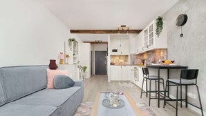 Ein modernes Wohnzimmer mit einer Couch, einem Couchtisch und einer Küchenzeile mit Esstisch und Stühlen.