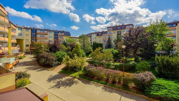 Un complejo residencial con varios edificios de apartamentos, un camino pavimentado y abundante vegetación bien cuidada.
