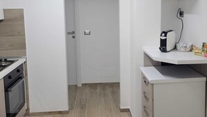 A compact kitchen with a stove, oven, and a coffee maker on a counter. - beb dei sogni (Cosenza)