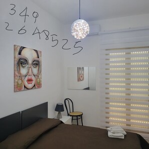 A modern bedroom with a bed, a chair, a desk, and a large window with blinds. - beb dei sogni (Cosenza)