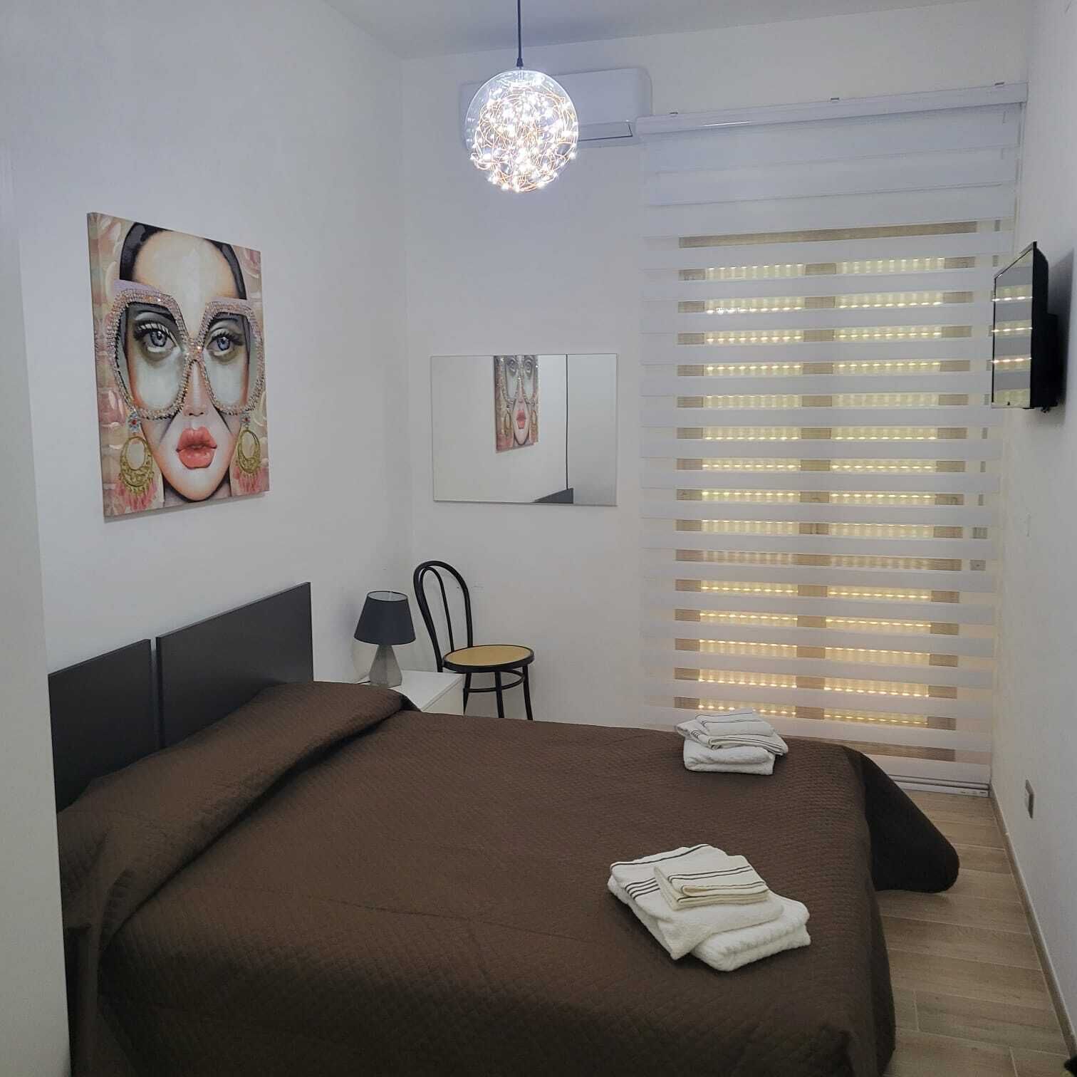 A modern bedroom with a large bed, a desk, a chair, and a TV mounted on the wall.
