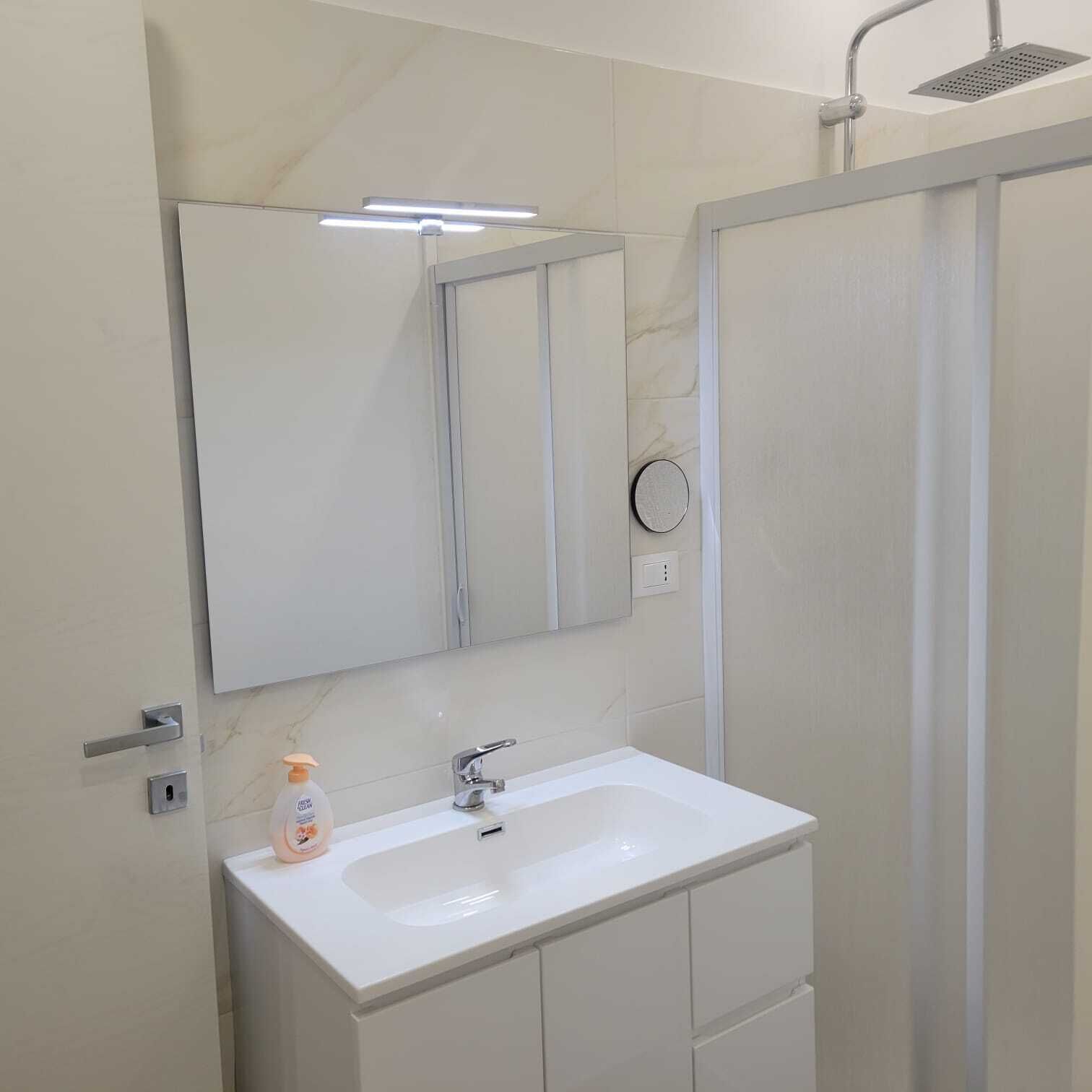 A bathroom with a white sink, a mirror, and a shower.