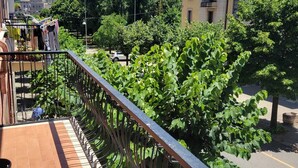 A balcony with a metal railing overlooking a street with parked cars and greenery. - beb dei sogni (Cosenza)