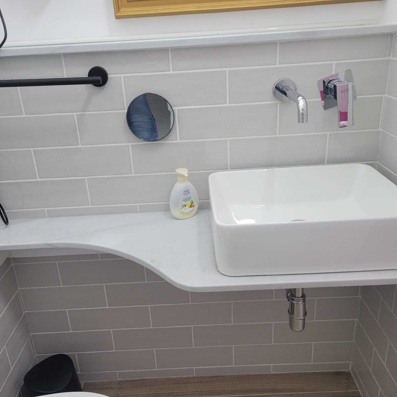 A bathroom with a white sink, a mirror, and a towel rack.