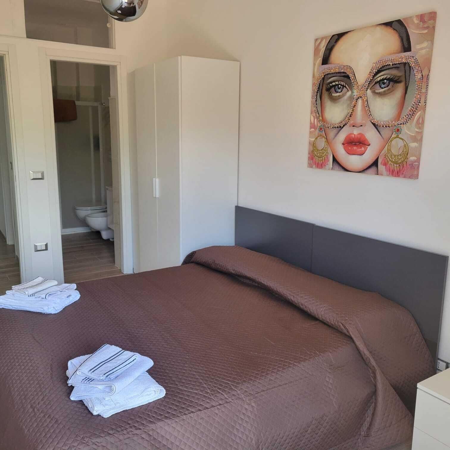A bedroom with a bed, a wardrobe, and a bathroom visible through an open door.