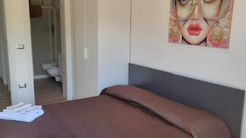A bedroom with a bed, a wardrobe, and a bathroom visible through an open door.