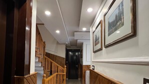 A hallway with wooden paneling, a staircase, and a door leading to another room. - wildflower villa (Anantnag)