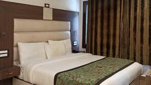 A hotel room with a large bed, a wooden headboard, a nightstand, and a patterned throw blanket. - wildflower villa (Anantnag)