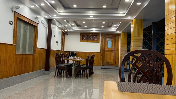 A spacious conference room with a polished marble floor, wooden panel walls, and a modern ceiling with recessed lighting. - wildflower villa (Anantnag)