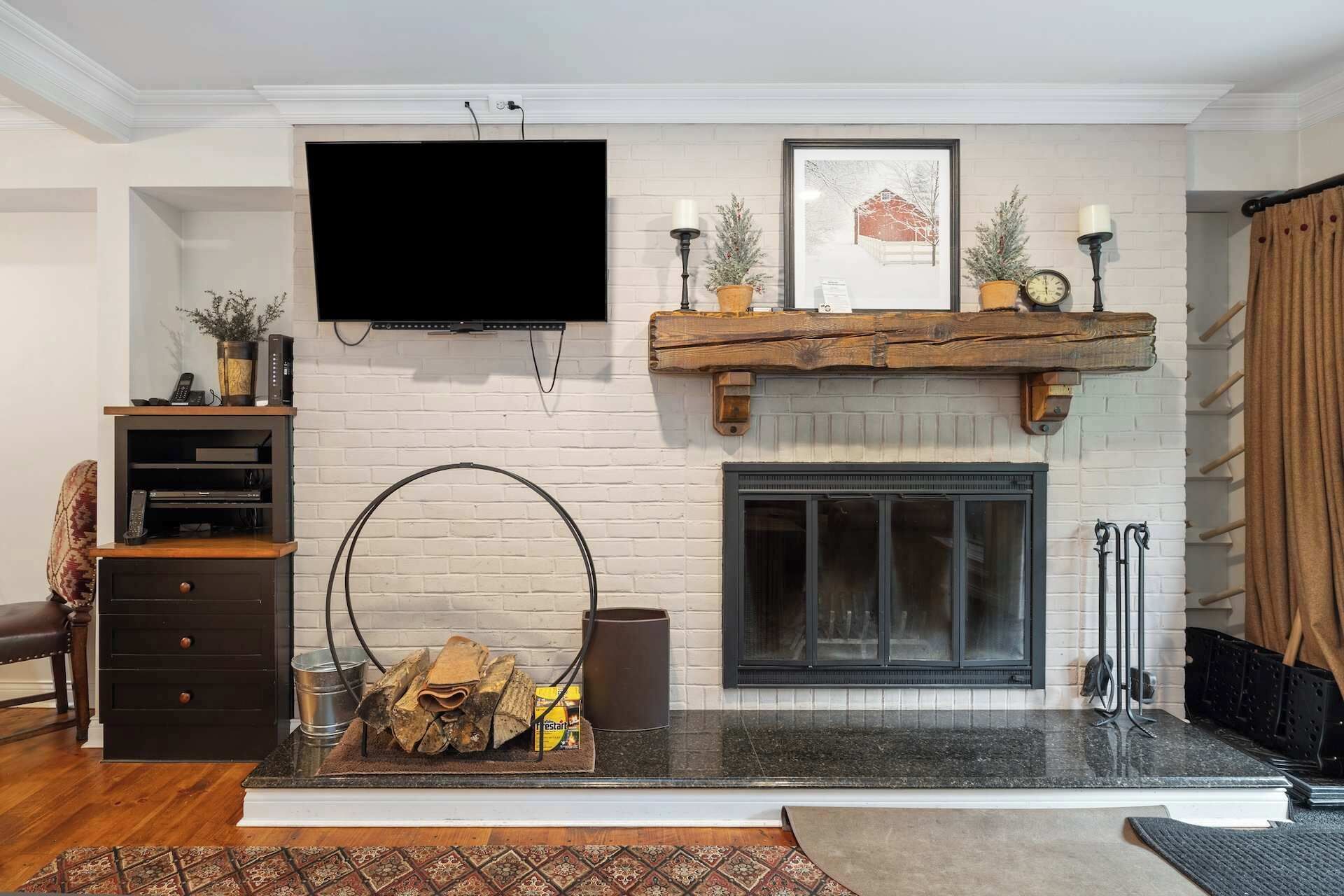 A living room with a fireplace, a mounted TV, and a wooden mantelpiece.