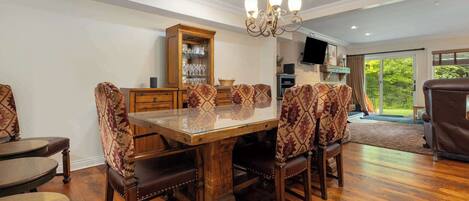 Un coin repas avec une table et des chaises en bois, un lustre et une vue sur l’extérieur grâce à une porte vitrée.