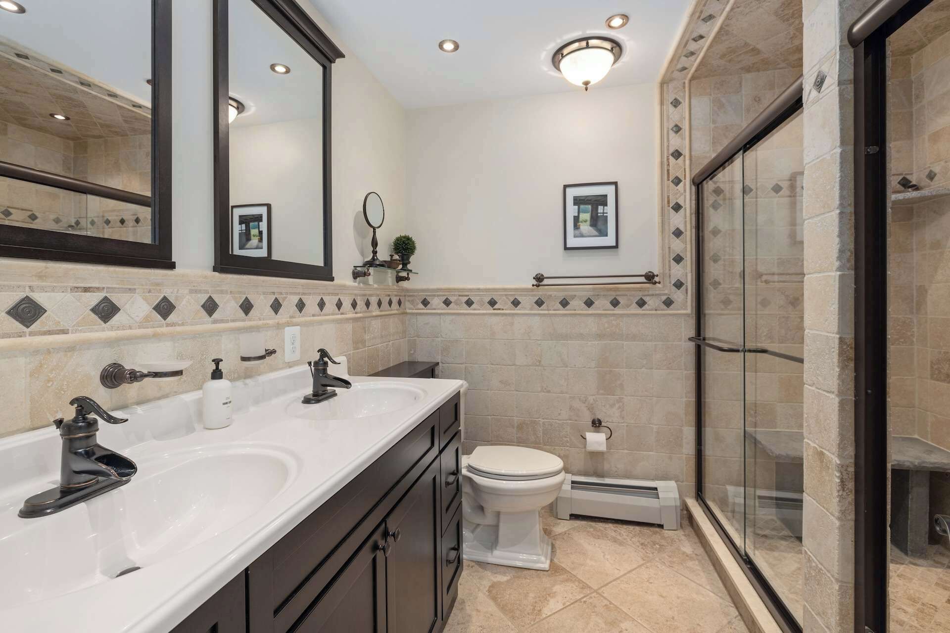 A modern bathroom with two sinks, a toilet, and a glass-enclosed shower.