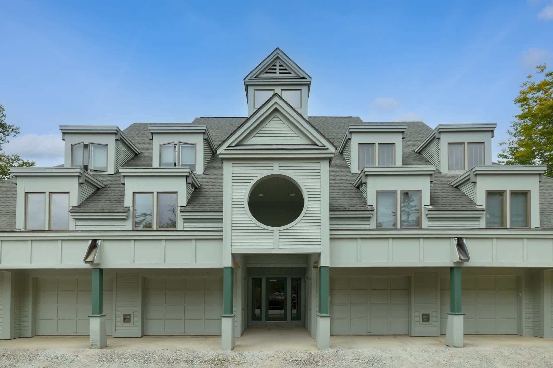 A multi-story building with a central circular window, multiple garage doors, and a symmetrical facade.