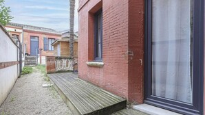 Un estrecho callejón con un banco de madera, un edificio de ladrillo rojo con una ventana y una puerta.