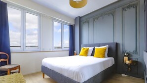 A bedroom with a large bed, a chair, and a bedside table.
