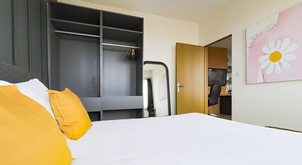 Quarto de hotel com cama, guarda-roupa, escrivaninha e cadeira.