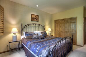 A bedroom with a bed, two bedside tables, a wooden wardrobe, and a ceiling light.