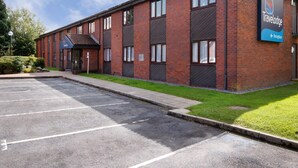 A Travelodge hotel with a brick facade, a reception area, and a parking lot.