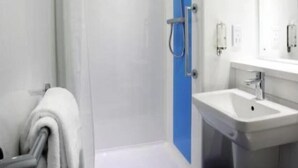 A modern bathroom with a glass-enclosed shower, a white sink, and a towel rack.