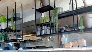 A kitchen with black metal shelves holding plants and kitchenware. - This is New England! (Armidale)