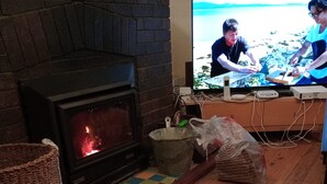 A cozy living room with a fireplace, a television, and a wooden floor. - This is New England! (Armidale)