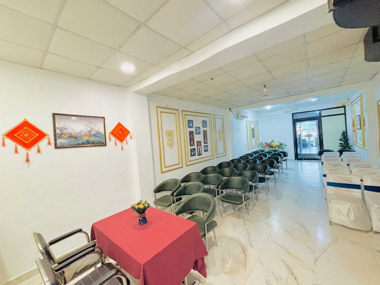 A hotel room with a tiled floor, a red table, and a chair.