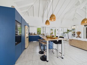 A modern kitchen with a blue accent wall, a central island, and pendant lighting.