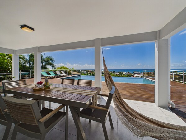 A covered outdoor area with a pool, lounge chairs, and a hammock.