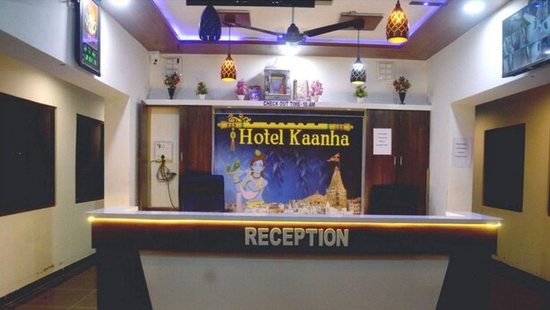 Een receptiebalie bij Hotel Kaanha, met een bord erboven, een plafondventilator en hangende pendelverlichting.