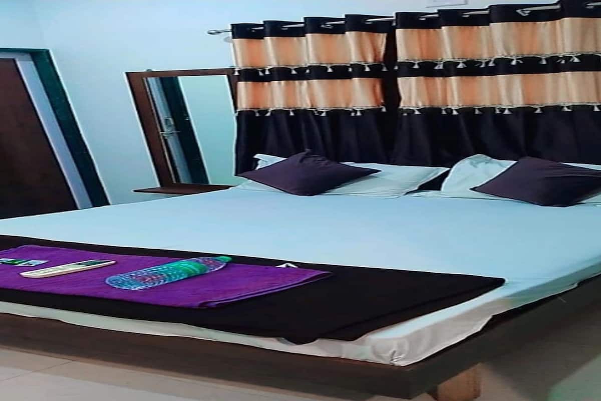 A neatly made bed with a white sheet, a purple blanket, and a pillow.