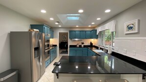 Una cocina moderna con armarios color turquesa, electrodomésticos de acero inoxidable y encimera negra.