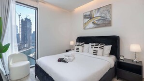 Een moderne hotelkamer met een groot bed, uitzicht op de stad en een schilderij aan de muur.
